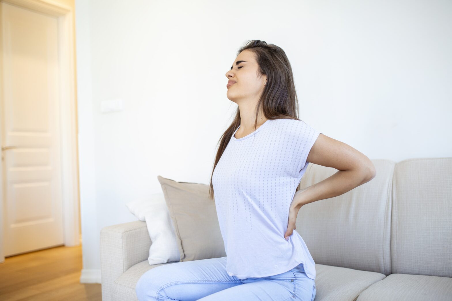 Femme avec les mains posées sur le dos à cause de douleurs chroniques de dos