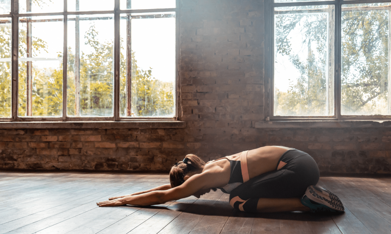 Yogiste à sa séance de Hatha Yoga, allongée contre le parquet avec un mur en brique en arrière plan