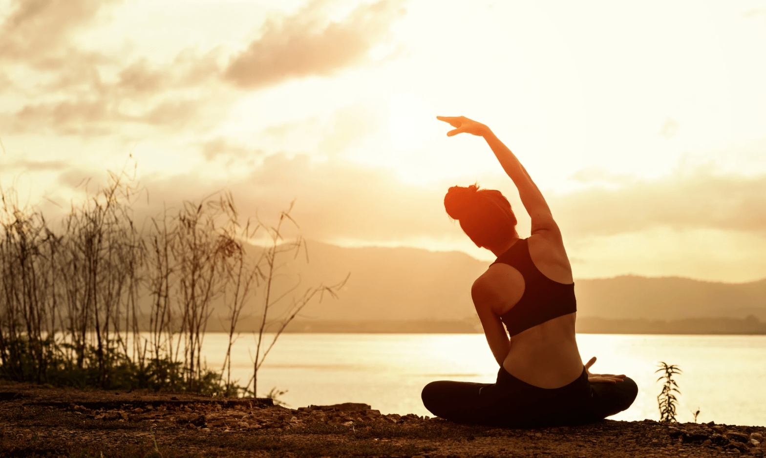 Femme devant un lac, face au soleil, séance de Jivamukti Yoga