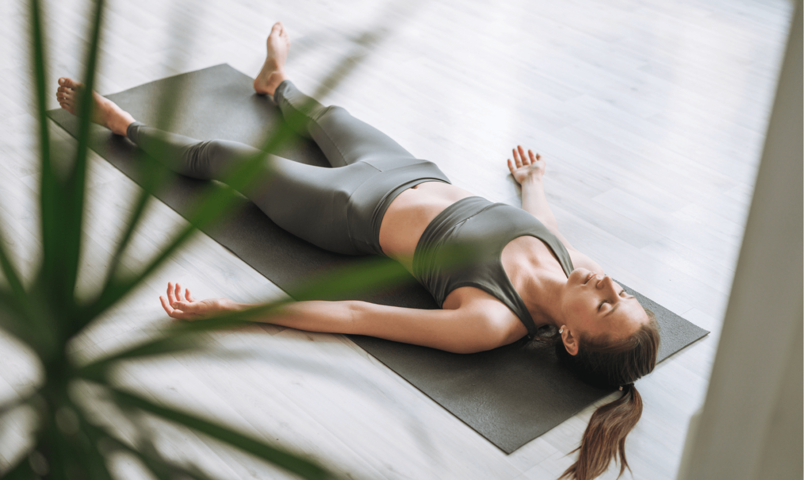 Femme allongée sur le dos, séance de Nidra Yoga en salle avec tapis de yoga