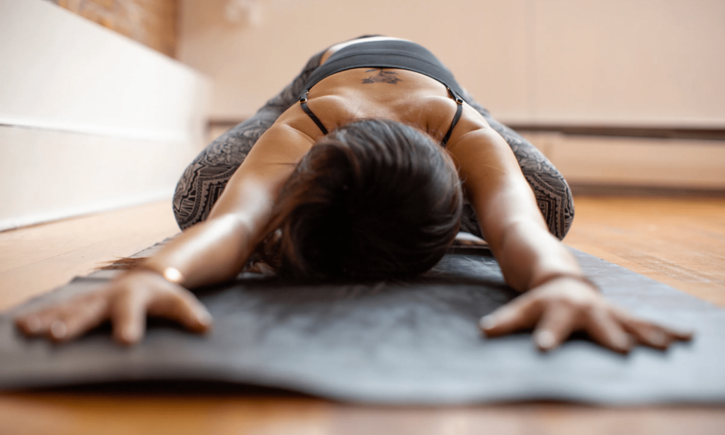 Femme allongée, séance de Power Yoga en salle avec tapis de yoga