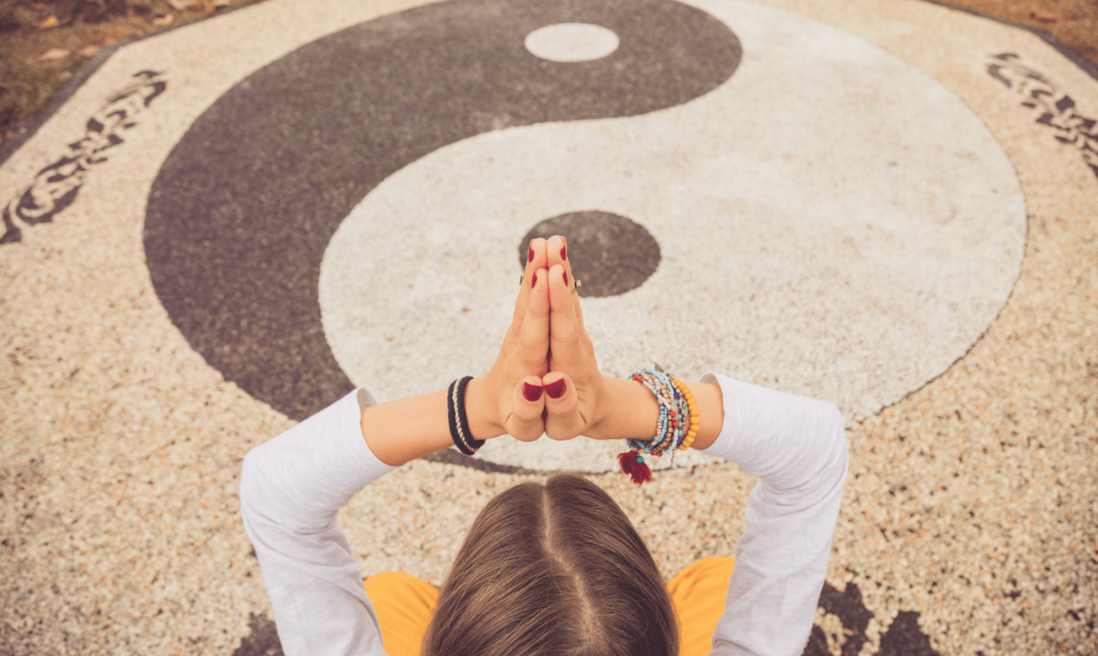 Yogiste à sa séance de Yin Yoga devant un tapis de yoga avec le Yin et le Yang