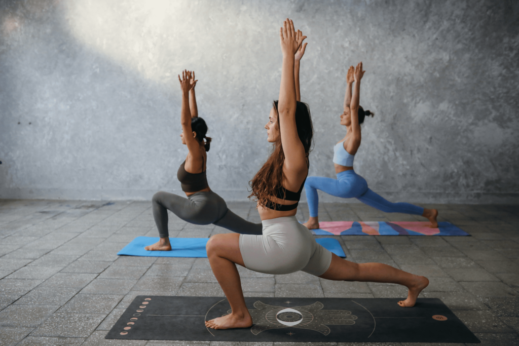 Groupe de femmes effectuant la pose de yoga du Virabhadrasana 1 sous la supervision d'une coach