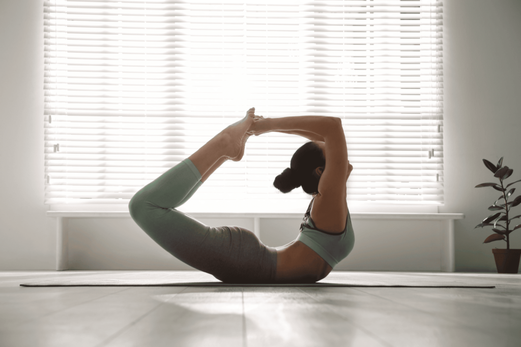 Femme en posture de l’arc au sol dans un studio de yoga.