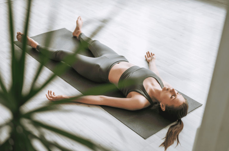 Femme allongée en Shavasana dans un studio de yoga.