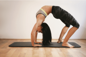 Femme en Sethubandhasana dans un studio de yoga.