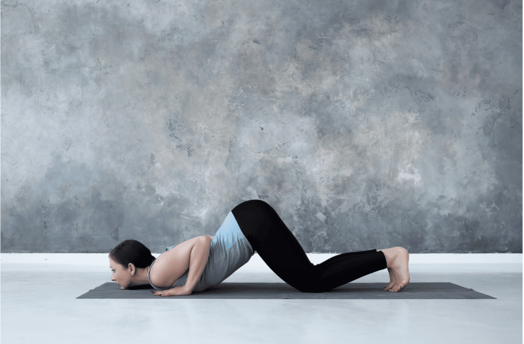 Femme en Ashtanga Namaskara sur un tapis de yoga.