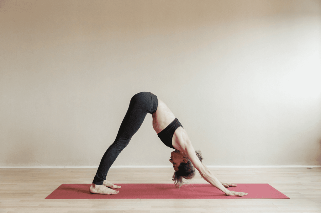 Femme en Adho Mukha Svanasana dans un studio de yoga.