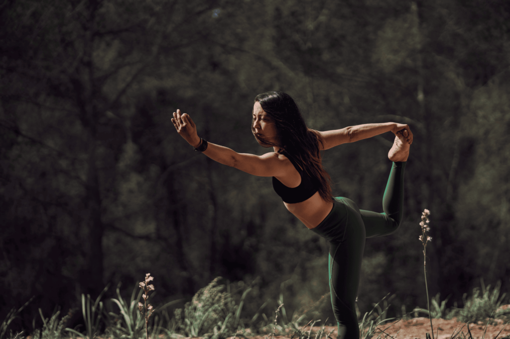 Femme en position de l'arc debout dans une forêt.