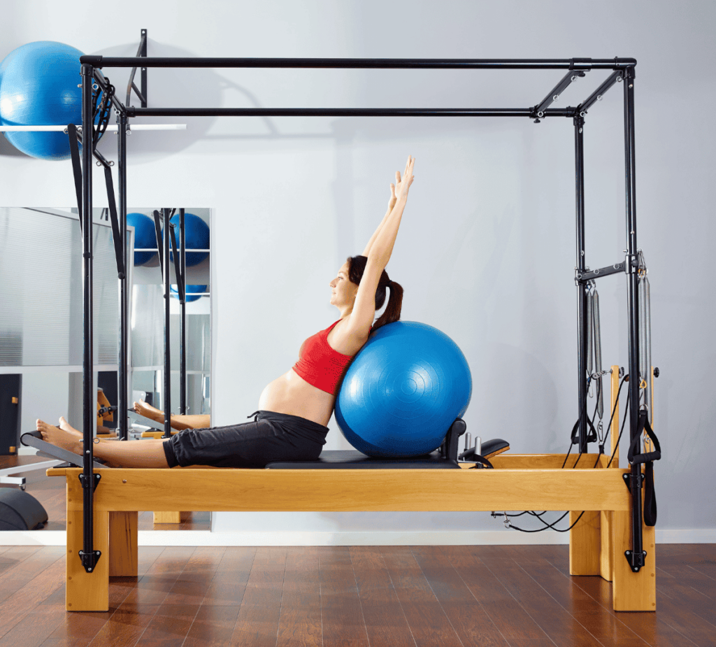 Femme enceinte pratiquant le pilates sur une machine reformer.