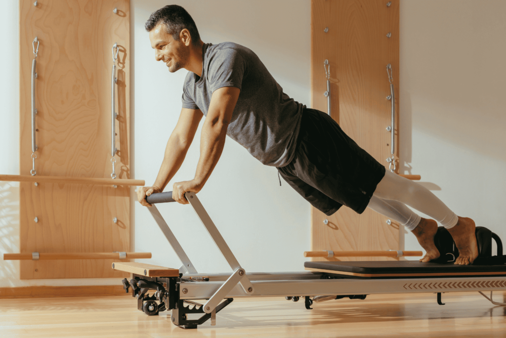 Homme utilisant une machine reformer pour le pilates.