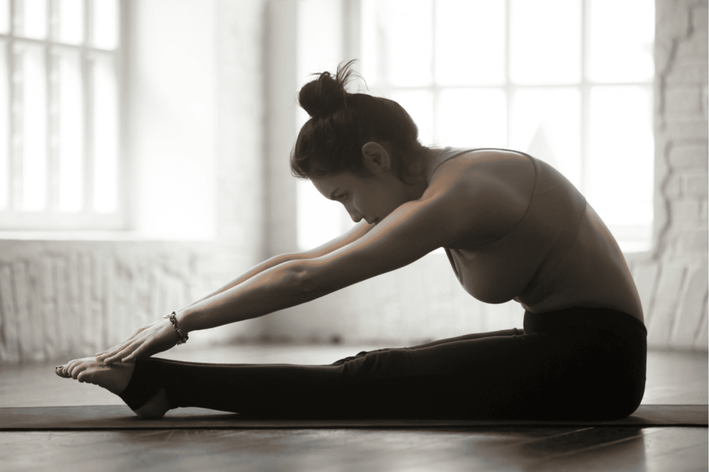 Étirement du dos avec le Spine Stretch Forward, assis jambes écartées et bras tendus.